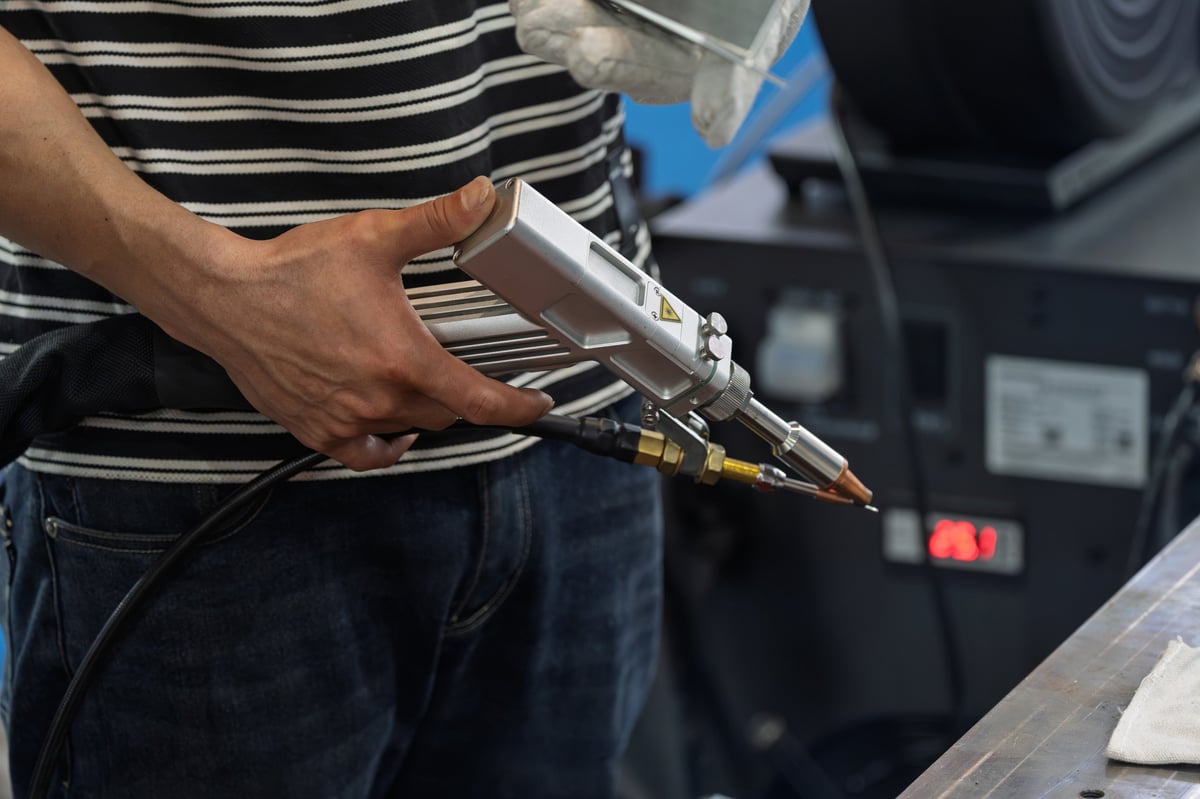Workers holding laser welding guns performing welding work