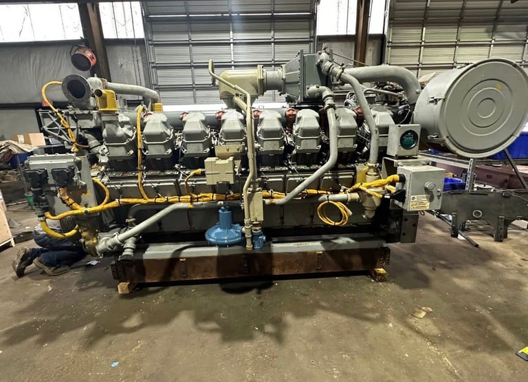 Large industrial diesel engine with yellow and black components mounted on steel base in warehouse setting